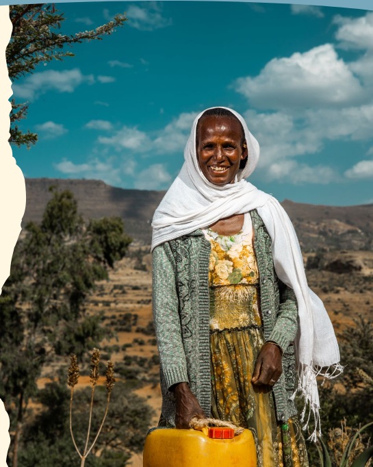 A woman standing outdoors with a yellow water container
